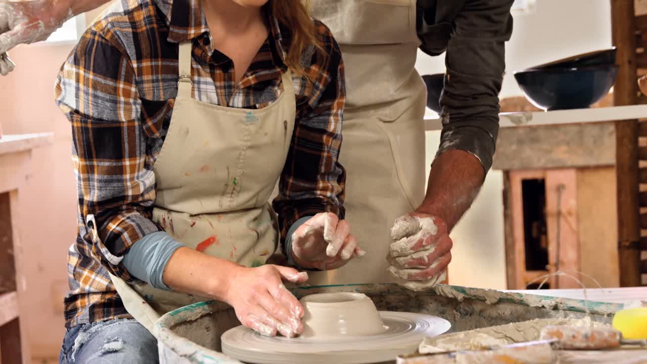Male potter assisting female potter