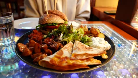 Close-up-of-big-vegetarian-appetizer-dish-with-burger,-potato,-quesadilla