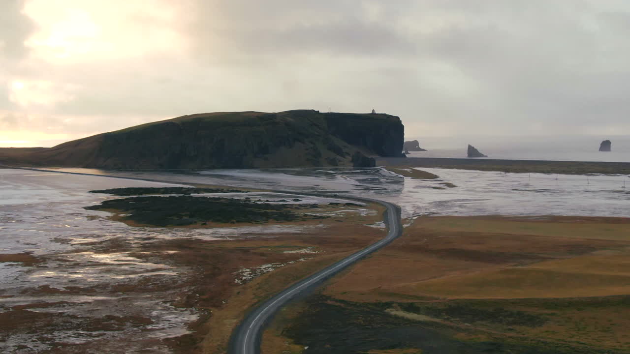 아이슬란드 의 먼 곳 에 큰 언덕 이 있는 두 개의 물체 를 가로지르는 황폐 한 지역 을 가로지르는 도로