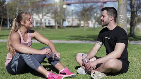 two smiling young people giving high five while sitting at park.