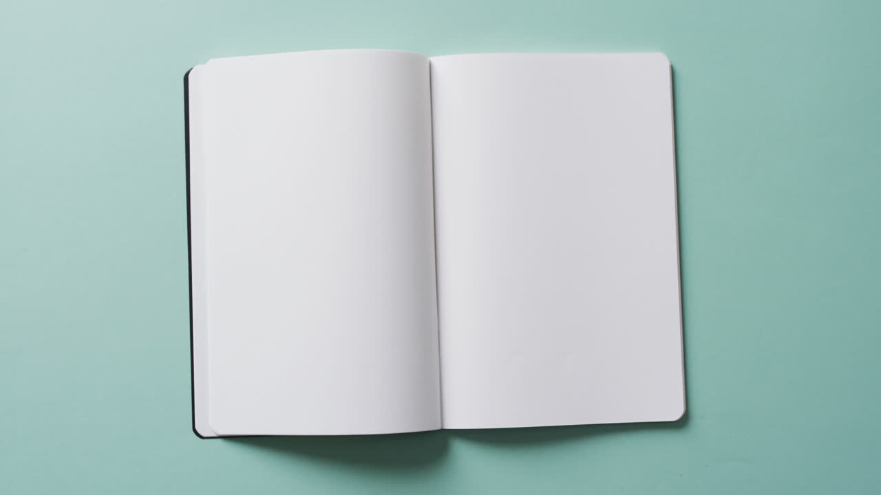Close up of open blank book with copy space on green background in slow motion