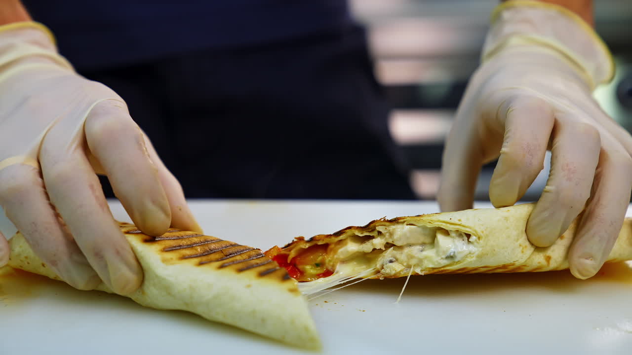 Tasty shawarma with tomatoes, peppers and sauces that make up its composition are laid out on a lacquered table cut in a half.