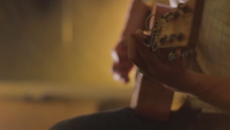 man playing acoustic guitar focused on head