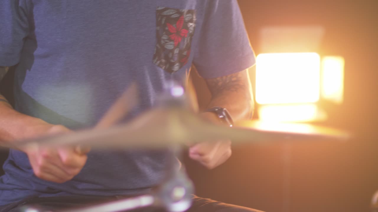 primer plano de un baterista profesional tocando un redoble de tambor en un platillo de paseo con una cálida luz led en el fondo
