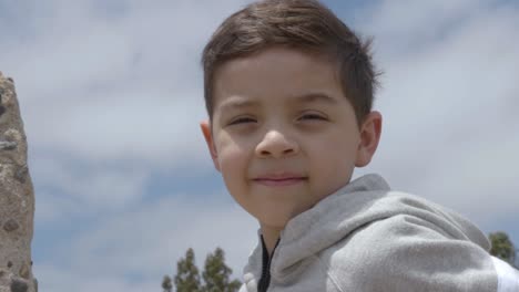 Little-boy-looking-at-camera-in-the-daytime-while-the-wind-blows