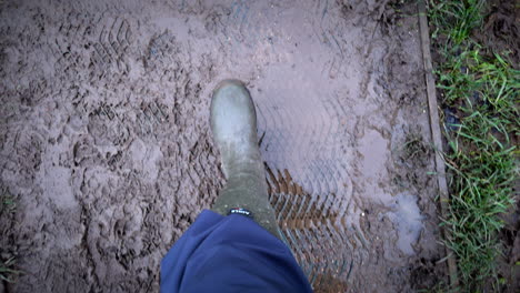 muddy conditions after heavy rainfall as a rambler wearing wellington boots walks in the english countryside