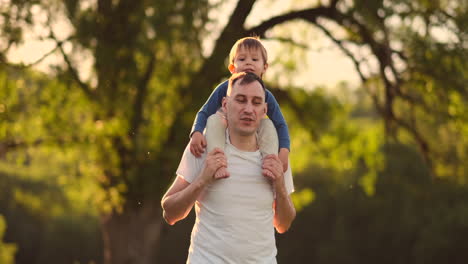 Manos-De-Papá-Sosteniendo-A-Un-Pequeño-Hijo-Lindo,-Feliz-Y-Sonriente,-Jugando-Juntos-En-El-Campo-Natural,-Tiro-En-Primera-Persona,-Familia-Despreocupada,-Disfrutando-Del-Fin-De-Semana,-Relajándose,-Pasando-Un-Buen-Rato-Al-Aire-Libre,-En-ángulo-Alto.