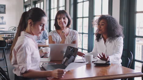 businesswomen having informal meeting around table in coffee shop