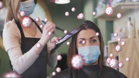 Animation-of-coronavirus-cells-over-caucasian-female-hairdresser-and-woman-wearing-face-masks