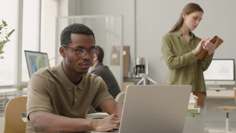 man using laptop sitting at desk in the office