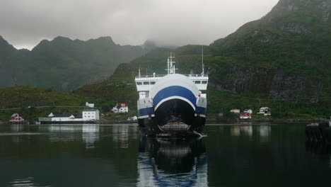 car ferry approaching the dock and opening its front bow door in the lofoten islands on a cloudy summer day, moskenes, norway