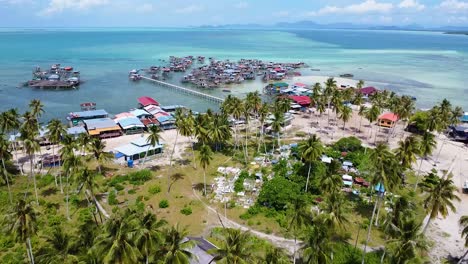 Revealing-flyover-shot-of-a-Bajau-Laut-community-from-land-to-their-water-village-in-Oulau-Omadal,-Sabah,-Malaysia