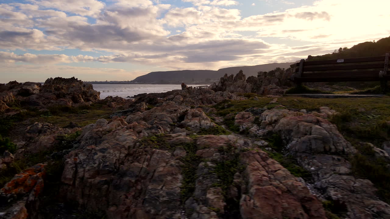 hombre en un afloramiento rocoso en la escarpada costa de hermanus observación de ballenas, puesta de sol aérea