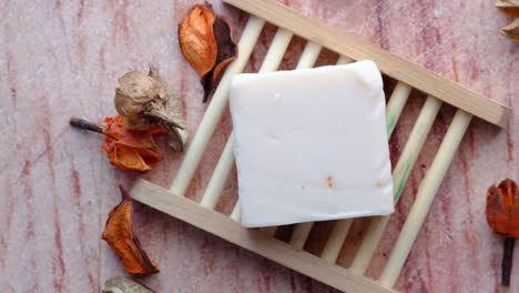 barra blanca de jabón en un plato de jabón de madera con flores secas