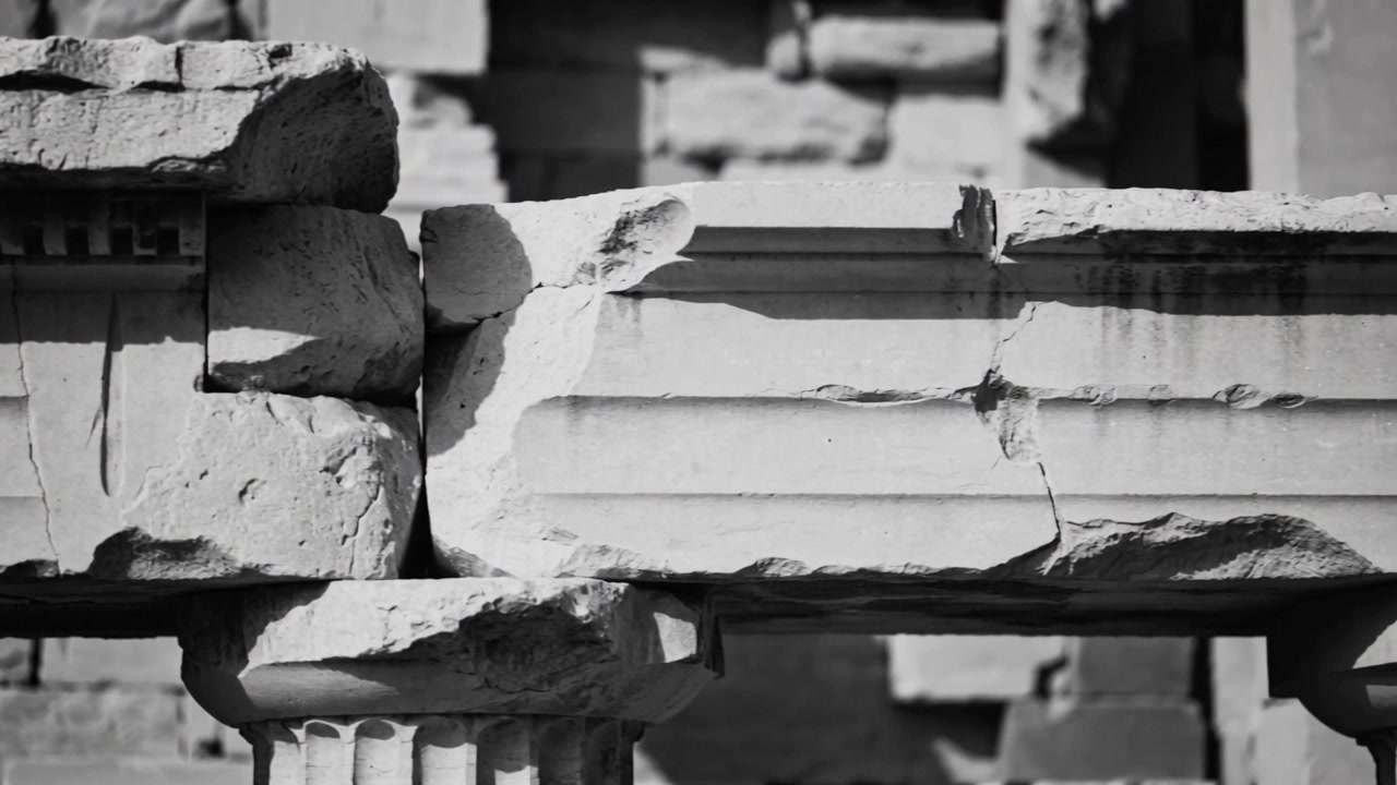 Pulling back as shot starts camera tilting down revealing cracked lintel, column capital at ruin