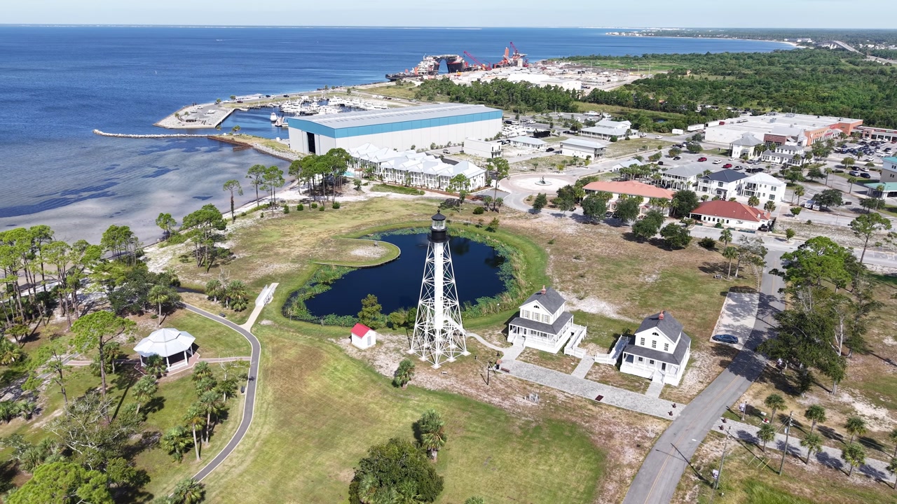 Drone orbit around Cape San Blas Lighthouse and local houses near shoreline and artificial pond, Port St. Joe, Gulf County, Florida, USA