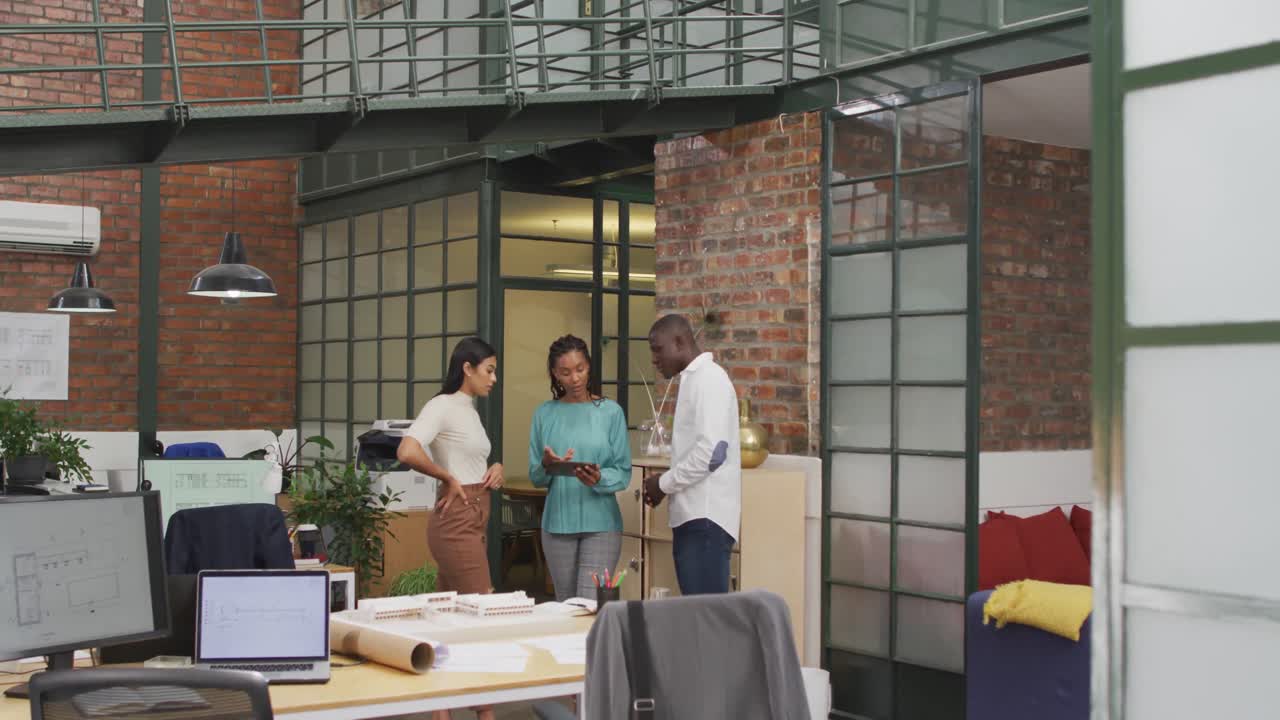 Happy diverse architects using tablet and discussing work at office