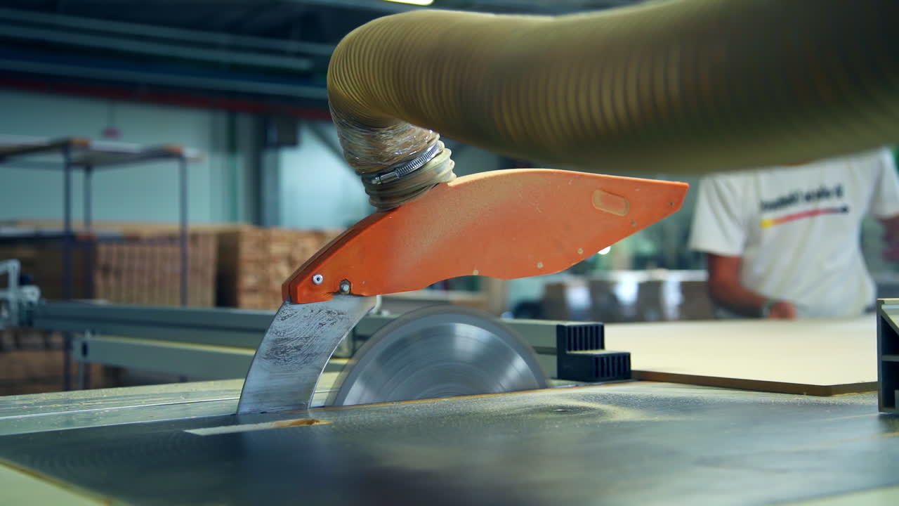 Machine-tool for cutting wood. Man pushing a wooden board to cut it with automatic saw equipment. Blurred backdrop.