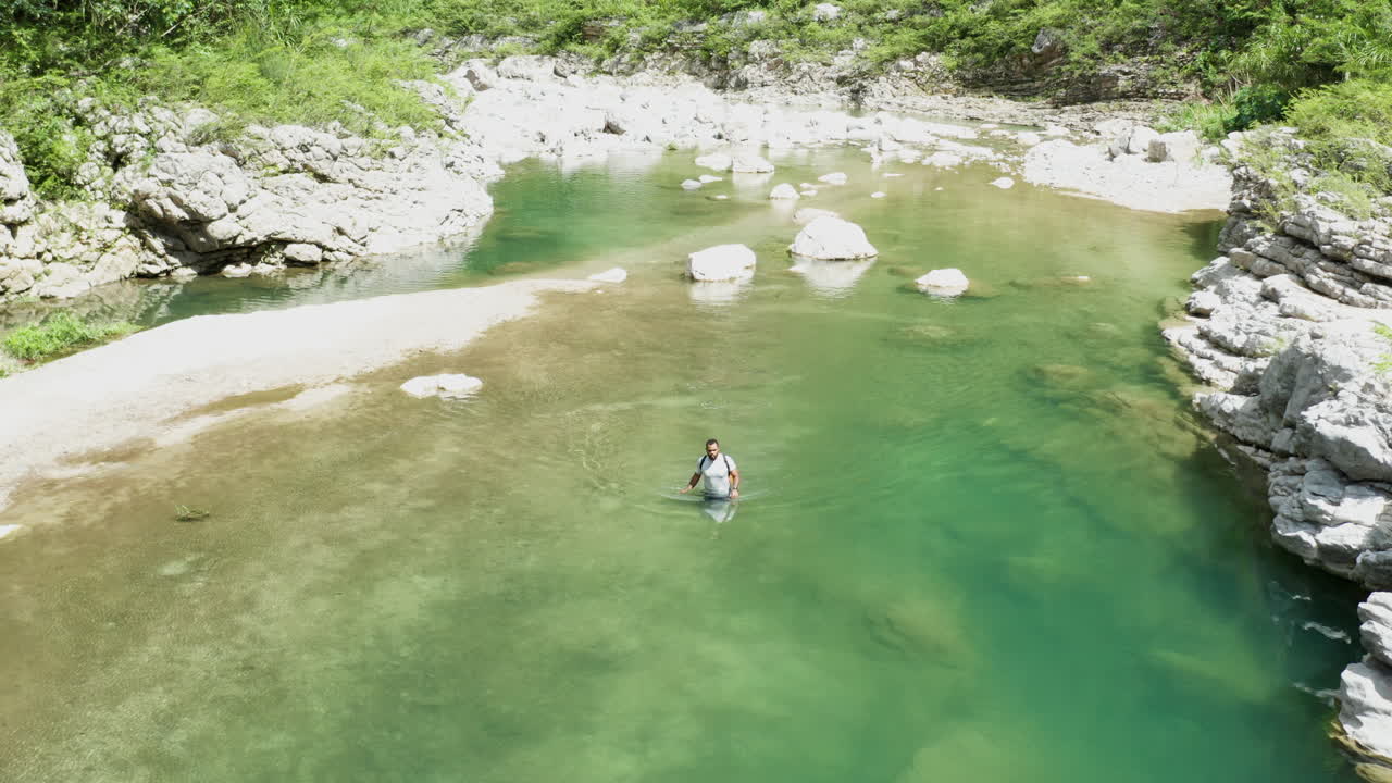 광야에 숨겨진 멋진 열대 석호로 더 깊이 방황하는 남자