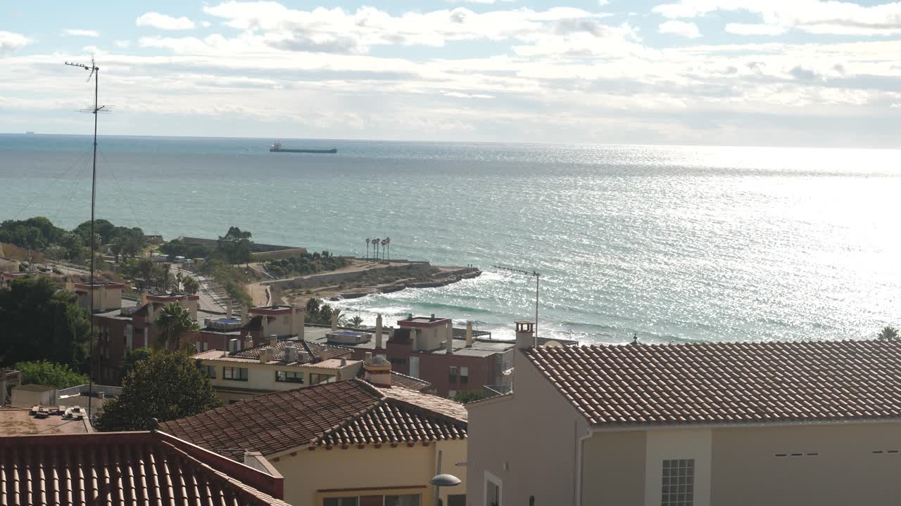 Deniz ve uzaktaki kargo gemisiyle bir kıyı kasabasının panoramik görünümü