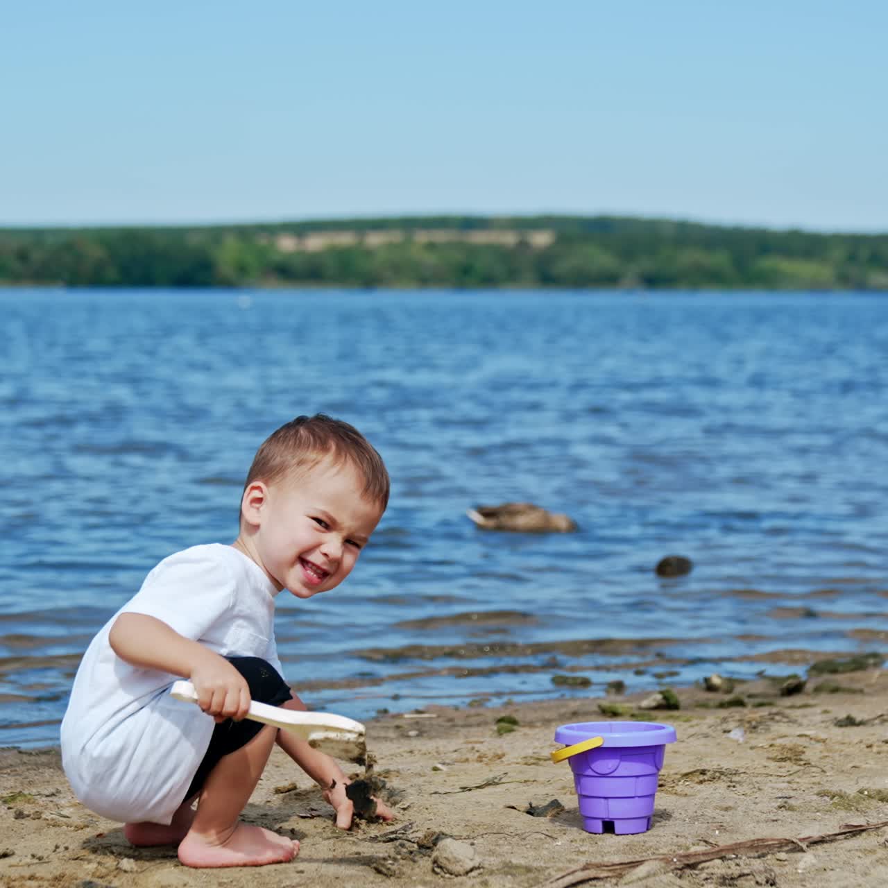 Small boy on river beach playing. Little child summer lifestyle