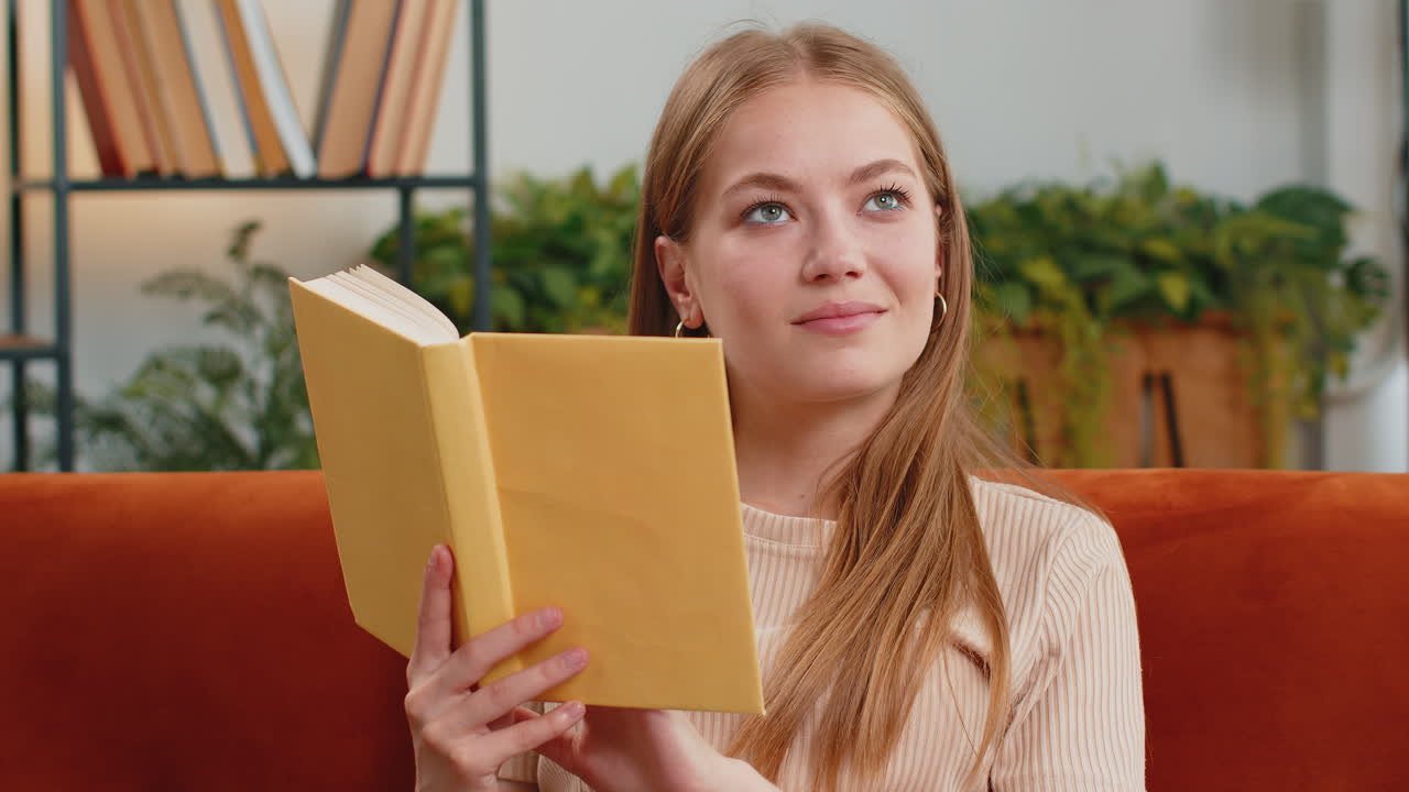 mujer joven leyendo un libro interesante pasando las páginas sonriendo disfrutando de la literatura descansando en el sofá