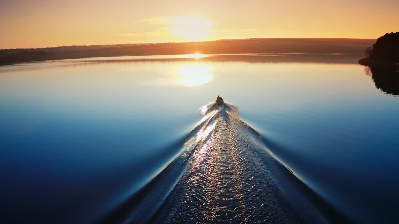 Motor boat floating on the river at sunset. Beautiful aerial view on the calm blue water in the evening. Boat moves along the river.