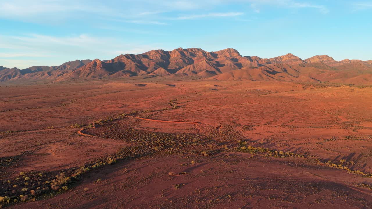 Vista aerea inversa con drone dell'aspro entroterra delle Flinders Ranges all'ora d'oro, Australia Meridionale