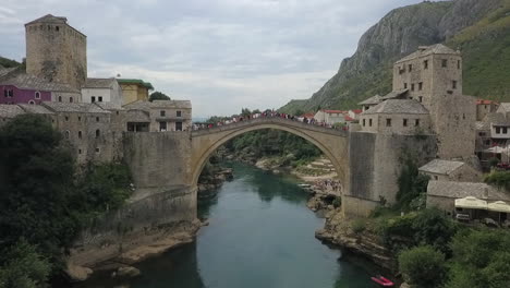 tourists, locals gather on mostar old bridge high over neretva river