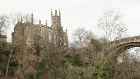 Pan-right-to-left-from-beneath-the-Dean-Bridge-across-to-Rhema-Christian-Centre-Church-on-an-overcast-day-in-Edinburgh,-Scotland