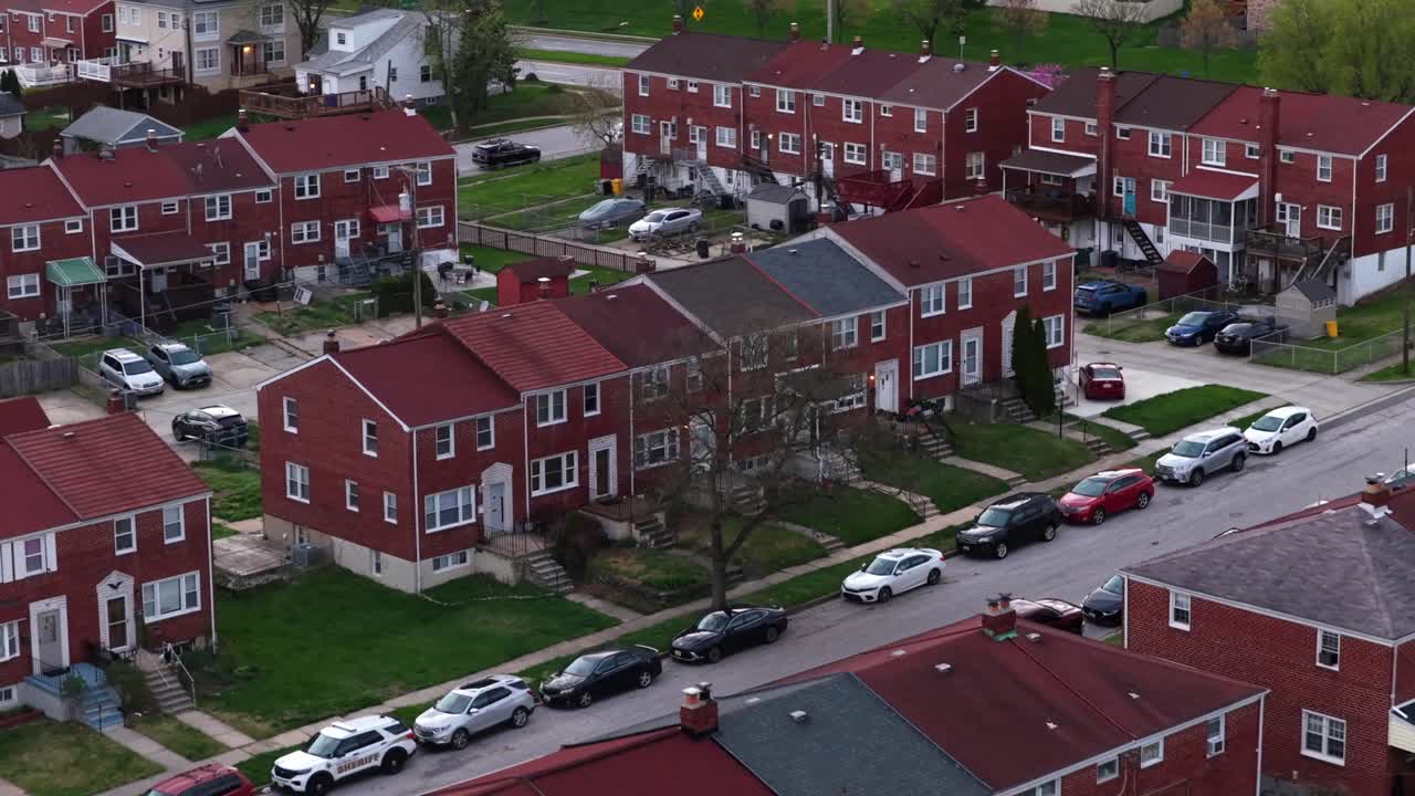 Overflyvning af rødstensrækkehuse og parcelhuse i et forstadskvarter i Baltimore, der viser boligindretning, verandaer og gader om foråret i Maryland, USA. Parkerede biler på vejene
