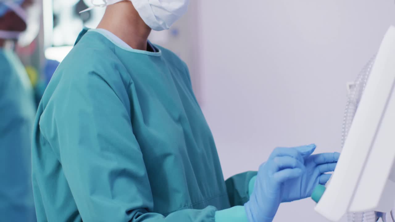 video de una asistente quirúrgica biracial preparando equipos electrónicos en el quirófano