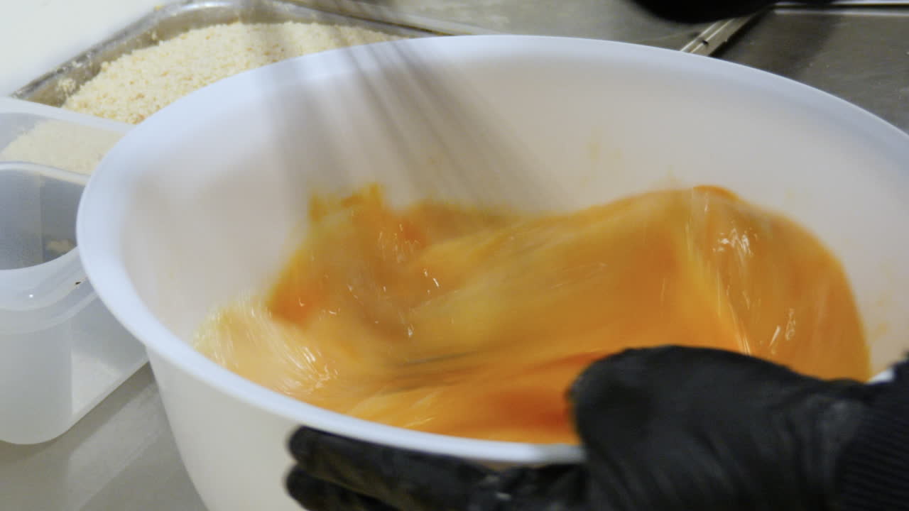 mujer batiendo huevos con un bigote en una cocina profesional
