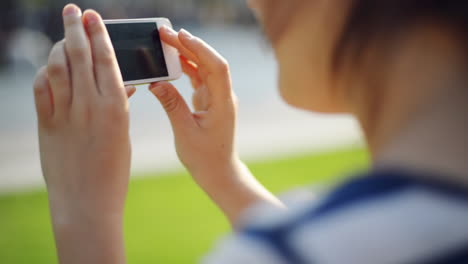 mujer enviando mensajes de video por teléfono móvil en el parque de la ciudad