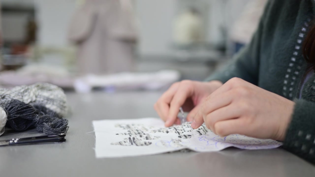 A fashion designer working at a desk painting ideas while focusing on design development