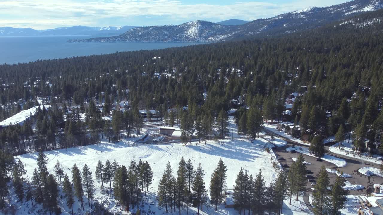 Aerial drone shot, flying over the woods towards the crystal clear lake in Lake Tahoe, Nevada-California