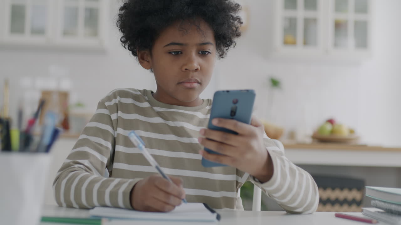 Child Doing Homework on Smartphone in Kitchen