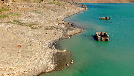 aerial of low water level and exposed lakebed with vibrant turquoise reservoir edge
