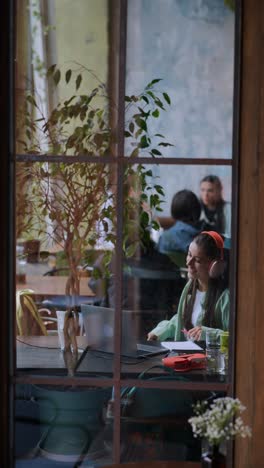 mujer trabajando en un café con auriculares