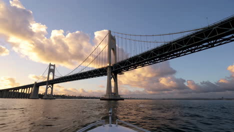 panoramic view of a large suspension bridge from a boat at sunset