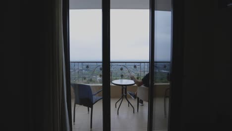 man drinking coffee on a hotel balcony with a view