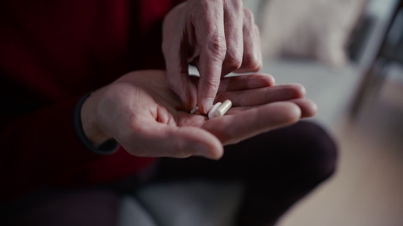 Primo piano delle mani di una persona anziana che tengono e smistano pillole
