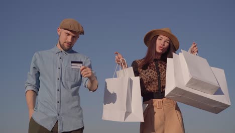 tema de compras: pareja con tarjeta de crédito y bolsas de compras