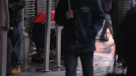 homeless person in the street. new york city commuters. wet day, umbrellas. manhattan nyc. slow motion.