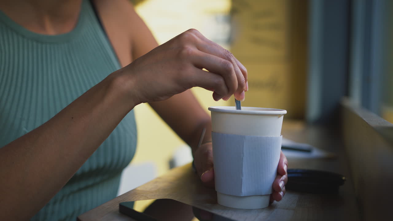 cerrar el cliente femenino en la ventana de la cafetería agitando bebida caliente