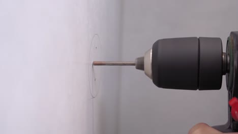 el artesano ha dibujado un círculo con lápiz y ha hecho marcas de x en la pared. el trabajador comienza a perforar agujeros en la superficie para insertar pernos y colgar estantes o ganchos, instalar muebles, cerrar.