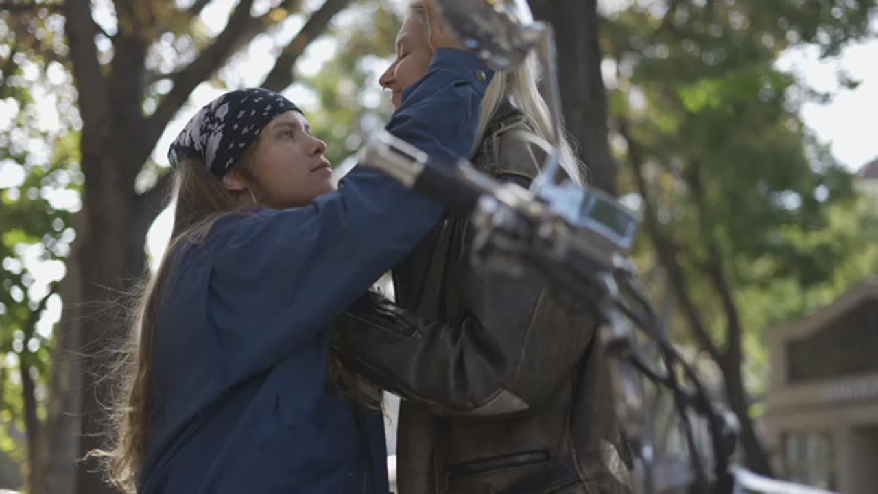 두 젊은 여성이 도시에서 오토바이에 타고 키스하고 재미를 즐기고 있습니다.