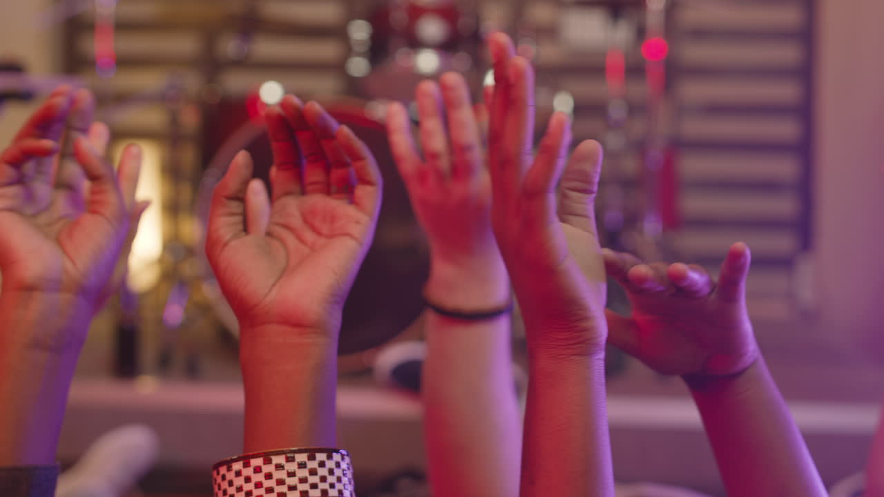 cerca de amigos multiétnicos irreconocibles moviendo sus manos levantadas en el aire mientras están acostados en el suelo durante el ensayo en el estudio de grabación 1