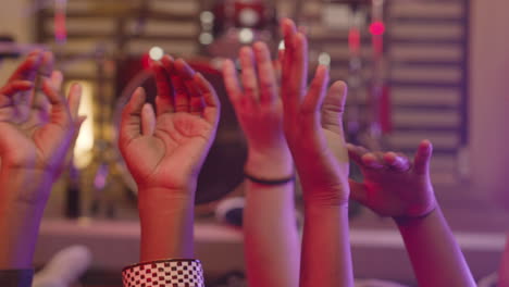 Close-Up-Of-Unrecognizable-Multiethnic-Friends-Moving-Their-Raised-Hands-In-The-Air-While-Lying-On-The-Floor-During-Rehearsal-In-Recording-Studio-1