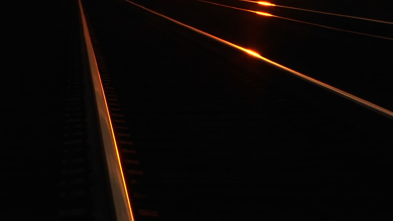 las vías del tren brillan bajo la luz del sol de la hora dorada